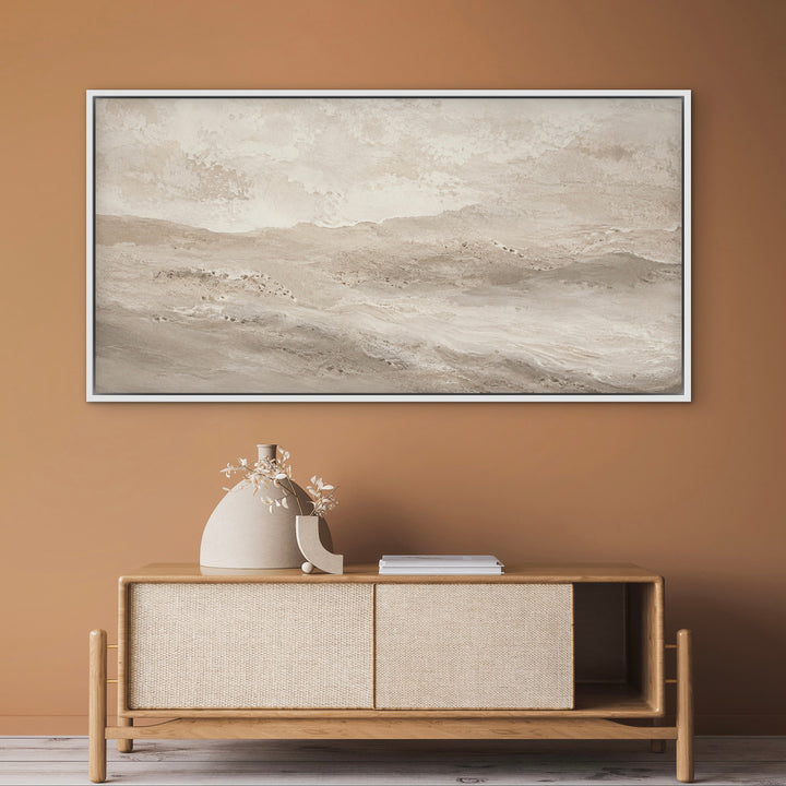 Dune sand-toned canvas in a white frame above a woven sideboard