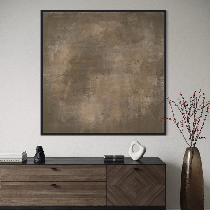 Framed abstract art piece on a wall above a wooden cabinet with decorative items.