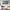 Living room with a white sofa, wooden coffee table, and abstract beach painting on the wall.