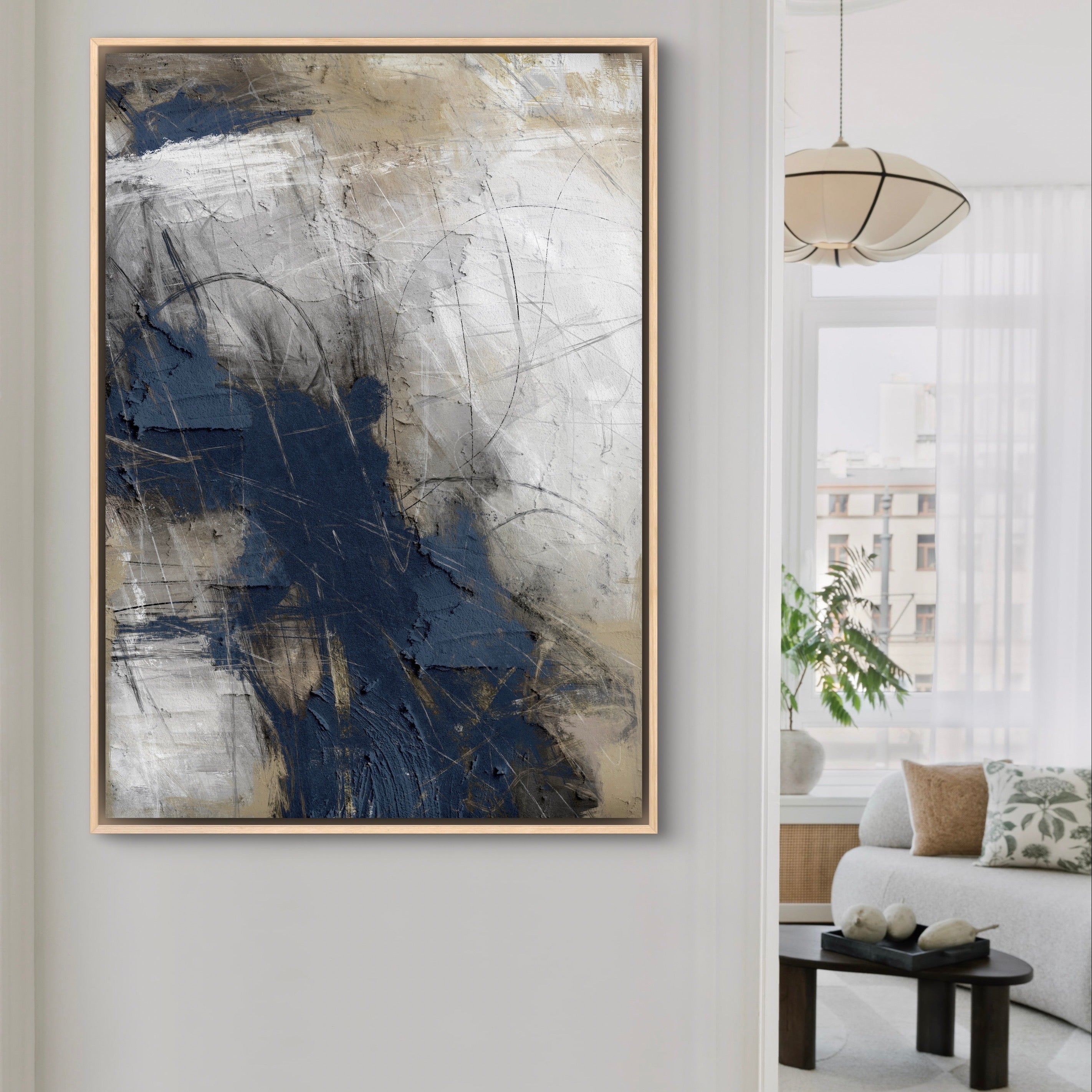 Modern Abstract Art Framed Canvas Styled with a Cream Sofa, Round Black Coffee Table, Botanical Pattern Pillows, and a Soft Pendant Light. Perfect for a Minimalist Living Room.