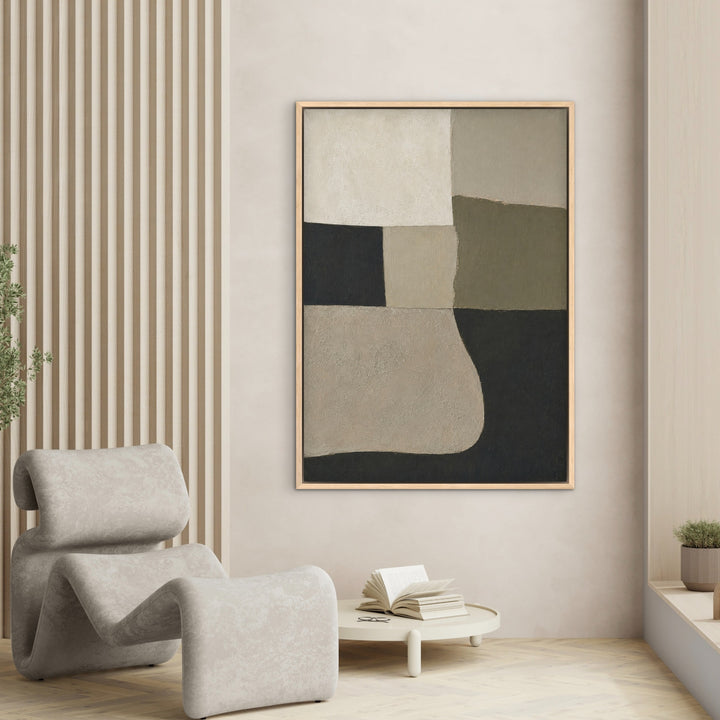 Quiet Geometry sage and charcoal portrait canvas in a natural frame beside a sculptural chair